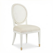 Load image into Gallery viewer, The Margo Dining Chair from Phillips Scott pairs a graceful oval silhouette with natural texture and tailored comfort. Crafted with a hardwood solid frame, it features a woven cane back, gently curved rear legs, and a generously upholstered seat in textured off-white fabric. Brass-finished caps on the front legs provide a subtle decorative accent.
