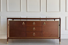 Load image into Gallery viewer, The Remi Server by Phillips Scott is a striking blend of mid-century influence and refined craftsmanship. Framed in solid walnut, the design features clean architectural lines softened by rounded corners and a warm, rich walnut finish. Brass detailing outlines the case and accents the hardware, creating a tailored contrast that elevates the entire silhouette.
