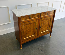 Load image into Gallery viewer, The Riley 2 Door Sideboard brings the graceful symmetry of European neoclassical design to a versatile, more compact scale. Crafted from mahogany solids with beautifully bookmatched cerejeira veneers, each door showcases a dramatic cathedral grain framed by hand-painted gold detailing. Two drawers keep smaller essentials close at hand, while the cabinet below provides generous concealed storage. Good Bones Furniture
