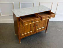 Load image into Gallery viewer, The Riley 2 Door Sideboard brings the graceful symmetry of European neoclassical design to a versatile, more compact scale. Crafted from mahogany solids with beautifully bookmatched cerejeira veneers, each door showcases a dramatic cathedral grain framed by hand-painted gold detailing. Two drawers keep smaller essentials close at hand, while the cabinet below provides generous concealed storage. Good Bones Furniture
