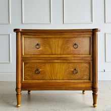 Load image into Gallery viewer, Elevate your bedside with the Riley Nightstand, a refined two-drawer piece that pairs timeless form with modern function. The front is clad in striking cerejeira veneer arranged in a radiant pattern and framed with hand-applied gold trim, while tapered legs finish with gilded caps for a subtle luxe note. Thoughtful scaling, warm mahogany tones, and elegant antique brass ring pulls make Riley an easy fit for both classic and contemporary bedrooms. Good Bones Furniture
