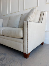 Load image into Gallery viewer, Crafted by renowned North Carolina manufacturer Sherrill Furniture, this custom upholstered sofa offers the exceptional comfort, craftsmanship, and timeless styling that have made the brand a favorite among designers and luxury furniture buyers. Upholstered in a versatile neutral fabric, the sofa features clean transitional track arms, elegant double-row nailhead trim, loose back cushions, and exposed tapered wood feet. Good Bones Furniture

