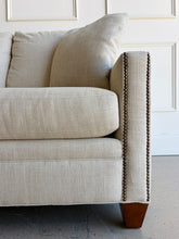 Load image into Gallery viewer, Crafted by renowned North Carolina manufacturer Sherrill Furniture, this custom upholstered sofa offers the exceptional comfort, craftsmanship, and timeless styling that have made the brand a favorite among designers and luxury furniture buyers. Upholstered in a versatile neutral fabric, the sofa features clean transitional track arms, elegant double-row nailhead trim, loose back cushions, and exposed tapered wood feet. Good Bones Furniture
