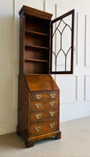 Load image into Gallery viewer, Classic English craftsmanship never goes out of style. This Southampton George III Style Secretary Bookcase is a beautifully proportioned piece that combines elegant display storage, a functional writing desk, and generous drawer storage within a refined, space-saving silhouette. Rich walnut and burl walnut veneers showcase striking natural grain throughout, while the leaded glass door, dentil crown molding, and original Chippendale-style brass hardware add timeless architectural character. Good Bones 
