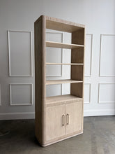 Load image into Gallery viewer, The Horizon Etagere by Theodore Alexander combines generous display space with a light, contemporary silhouette. Crafted from oak in a pale Day finish, its softly rounded frame and finely reeded details introduce texture while preserving the collection’s clean lines. Multiple open shelves provide ample room for books, art, and collected objects, while the two-door cabinet below offers convenient concealed storage. Good Bones Furniture
