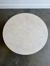 Load image into Gallery viewer, The Lucienne Cocktail Table by Theodore Alexander combines classical ornament with a light, graceful silhouette. Crafted from Khaya wood and richly figured Khaya swirl veneer, its round top rests above a fluted frieze accented with carved leaf motifs. Slender fluted legs connect the upper surface to a wide circular lower shelf.  Washed Blanchette finish. Good Bones Furniture
