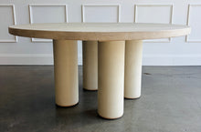 Load image into Gallery viewer, The Maxwell Round Dining Table by Theodore Alexander combines natural oak grain with distinctive shagreen texture and an architectural silhouette. Crafted from oak wood and oak veneers, the generous round top is finished in pale Cashmere, allowing its organic grain to remain visible. Four cylindrical supports feature a subtle shagreen surface in a tonal Dove finish. Good Bones Furniture

