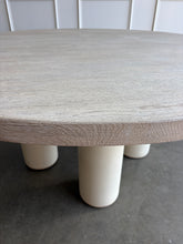 Load image into Gallery viewer, The Maxwell Round Dining Table by Theodore Alexander combines natural oak grain with distinctive shagreen texture and an architectural silhouette. Crafted from oak wood and oak veneers, the generous round top is finished in pale Cashmere, allowing its organic grain to remain visible. Four cylindrical supports feature a subtle shagreen surface in a tonal Dove finish. Good Bones Furniture
