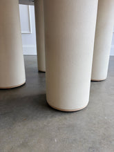 Load image into Gallery viewer, The Maxwell Round Dining Table by Theodore Alexander combines natural oak grain with distinctive shagreen texture and an architectural silhouette. Crafted from oak wood and oak veneers, the generous round top is finished in pale Cashmere, allowing its organic grain to remain visible. Four cylindrical supports feature a subtle shagreen surface in a tonal Dove finish. Good Bones Furniture

