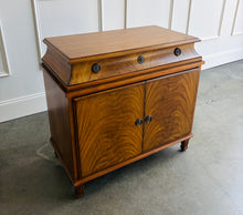 Load image into Gallery viewer, The Valencia Bedside Chest combines elegant architectural detailing with beautifully figured wood grain. Crafted from mahogany solids with richly patterned cerejeira veneers, it features two cabinet doors that open to reveal a spacious interior with one adjustable shelf. molded top, graceful concave frieze, decorative metal hardware, and fluted tapered feet. Good Bones Furniture

