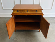 Load image into Gallery viewer, The Valencia Bedside Chest combines elegant architectural detailing with beautifully figured wood grain. Crafted from mahogany solids with richly patterned cerejeira veneers, it features two cabinet doors that open to reveal a spacious interior with one adjustable shelf. molded top, graceful concave frieze, decorative metal hardware, and fluted tapered feet. Good Bones Furniture
