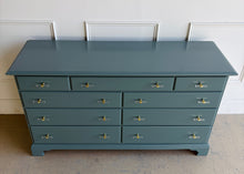 Load image into Gallery viewer, This vintage solid wood 9-drawer dresser has been professionally lacquered in Farrow &amp; Ball Inchyra Blue, a refined blue-green tone that brings depth and understated drama to any room. The clean, traditional lines pair beautifully with new lucite and brass handles, creating a balanced look that feels both classic and freshly updated. Each drawer offers generous storage, making this a functional statement piece for bedrooms, entryways, or living spaces. Good Bones Furniture
