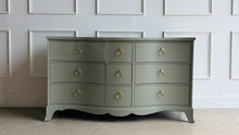 Load image into Gallery viewer, This vintage Table Rock dresser pairs classic construction with a fresh, tailored finish. Lacquered in Sherwin Williams Lauriston Stone, the muted green-gray tone gives the piece a soft, updated presence while still feeling timeless. The gently serpentine front adds movement and elegance, and the new solid brass ring hardware brings a polished contrast to the clean drawer layout. Good Bones Furniture
