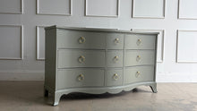 Load image into Gallery viewer, This vintage Table Rock dresser pairs classic construction with a fresh, tailored finish. Lacquered in Sherwin Williams Lauriston Stone, the muted green-gray tone gives the piece a soft, updated presence while still feeling timeless. The gently serpentine front adds movement and elegance, and the new solid brass ring hardware brings a polished contrast to the clean drawer layout. Good Bones Furniture
