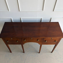 Load image into Gallery viewer, Antique bench made cherry sideboard with three drawers and tapered legs, shown in a bright white paneled room, featuring a clean architectural silhouette and warm natural wood finish. Good Bones Furniture
