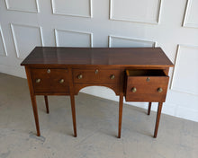 Load image into Gallery viewer, Antique bench made cherry sideboard with three drawers and tapered legs, shown in a bright white paneled room, featuring a clean architectural silhouette and warm natural wood finish. Good Bones Furniture
