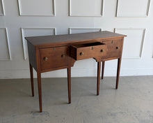 Load image into Gallery viewer, Antique bench made cherry sideboard with three drawers and tapered legs, shown in a bright white paneled room, featuring a clean architectural silhouette and warm natural wood finish. Good Bones Furniture
