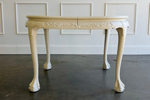 Load image into Gallery viewer, This vintage Chippendale-style dining table combines elaborate traditional detailing with a fresh, versatile finish. Professionally lacquered in Benjamin Moore Swiss Coffee darkened by 50%, it has a warm, creamy white appearance that highlights its carved details without feeling stark. Good Bones Furniture
