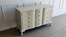Load image into Gallery viewer, This vintage 12 drawer dresser by Continental Furniture has been professionally lacquered in Benjamin Moore Natural Linen, giving the traditional silhouette a softer, updated presence while highlighting its elegant serpentine front and carved details. Resting on sculpted claw feet with fluted corner accents, new Hepplewhite hardware. Good Bones Furniture
