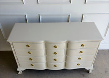 Load image into Gallery viewer, This vintage 12 drawer dresser by Continental Furniture has been professionally lacquered in Benjamin Moore Natural Linen, giving the traditional silhouette a softer, updated presence while highlighting its elegant serpentine front and carved details. Resting on sculpted claw feet with fluted corner accents, new Hepplewhite hardware. Good Bones Furniture
