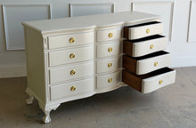 Load image into Gallery viewer, This vintage 12 drawer dresser by Continental Furniture has been professionally lacquered in Benjamin Moore Natural Linen, giving the traditional silhouette a softer, updated presence while highlighting its elegant serpentine front and carved details. Resting on sculpted claw feet with fluted corner accents, new Hepplewhite hardware. Good Bones Furniture
