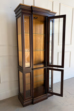 Load image into Gallery viewer, This vintage curio cabinet is a tall, architectural display piece designed to show off collections without overwhelming a room. A narrow footprint makes it an easy fit for dining rooms, living spaces, or entryways, while the glass-front design and interior light create a true “gallery” effect. Glass shelving and framed panels keep the silhouette light and refined, and the substantial crown and stepped base give it a classic, furniture-quality presence.

