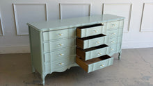 Load image into Gallery viewer, Elegant curves and generous storage give this vintage Dixie dresser a timeless presence, while its fresh custom finish makes it feel entirely current. Lacquered in a Benjamin Moore Saybrook Sage mix, the soft muted green highlights the dresser’s serpentine front, graceful cabriole legs, and classic French-inspired lines. New lucite and brass hardware. Good Bones Furniture
