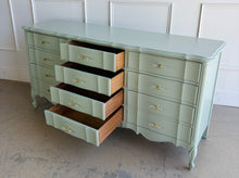 Load image into Gallery viewer, Elegant curves and generous storage give this vintage Dixie dresser a timeless presence, while its fresh custom finish makes it feel entirely current. Lacquered in a Benjamin Moore Saybrook Sage mix, the soft muted green highlights the dresser’s serpentine front, graceful cabriole legs, and classic French-inspired lines. New lucite and brass hardware. Good Bones Furniture
