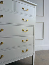 Load image into Gallery viewer, Vintage Dixie chest offers generous storage within a tall, space-conscious silhouette. Professionally lacquered in Benjamin Moore Swiss Coffee at 150% strength, its warm creamy-white finish complements the chest’s clean lines, inset drawer fronts, and tapered legs. Six drawers provide ample storage, while new solid brass drop-bail pulls add a polished contrast. Good Bones Furniture
