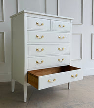 Load image into Gallery viewer, Vintage Dixie chest offers generous storage within a tall, space-conscious silhouette. Professionally lacquered in Benjamin Moore Swiss Coffee at 150% strength, its warm creamy-white finish complements the chest’s clean lines, inset drawer fronts, and tapered legs. Six drawers provide ample storage, while new solid brass drop-bail pulls add a polished contrast. Good Bones Furniture
