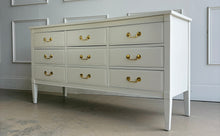 Load image into Gallery viewer, Vintage 9 drawer dresser by Dixie Furniture offers substantial storage within a timeless, beautifully proportioned silhouette. Professionally lacquered in Benjamin Moore Swiss Coffee at 150% strength, its warm creamy-white finish highlights the clean lines, inset drawer fronts, and tapered legs. Good Bones Furniture
