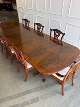 Load image into Gallery viewer, This vintage Drexel Heritage Nine Elms dining set showcases richly figured crotch mahogany veneer framed by contrasting banding. The expansive table rests on two ornately carved pedestal bases and includes three 22-inch leaves, extending it to an impressive 140 inches for large gatherings. Eight coordinating chairs—two armchairs and six side chairs. Good Bones Furniture
