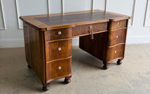 Load image into Gallery viewer, This vintage English-style pedestal desk features richly figured wood veneers, dramatic waterfall drawer fronts, and a gilt-tooled leather writing surface that gives the piece the feel of a collected European library. Influenced by Georgian Revival and campaign-style furniture, the desk blends traditional detailing with softer Art Deco curves, creating a silhouette that feels both timeless and distinctive. Good Bones Furniture
