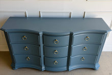 Load image into Gallery viewer, Vintage Ethan Allen dresser lacquered in Sherwin Williams Rain Cloud, the muted blue-gray color gives the piece a sophisticated, updated presence. The serpentine front adds movement across all nine drawers, while fluted corner details and a stepped base bring structure and depth. New brushed brass ring hardware. Good Bones Furniture
