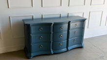Load image into Gallery viewer, Vintage Ethan Allen dresser lacquered in Sherwin Williams Rain Cloud, the muted blue-gray color gives the piece a sophisticated, updated presence. The serpentine front adds movement across all nine drawers, while fluted corner details and a stepped base bring structure and depth. New brushed brass ring hardware. Good Bones Furniture
