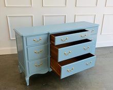 Load image into Gallery viewer, This vintage nine-drawer dresser by Ethan Allen combines generous storage with graceful traditional detailing. Professionally lacquered in a custom muted blue with soft gray undertones, the finish gives its classic silhouette a fresh, versatile look. Nine drawers provide abundant organized storage, while framed drawer fronts, a gently stepped top, curved apron, carved shell motif, and cabriole-style legs preserve its vintage character. Good Bones Furniture
