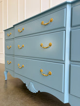 Load image into Gallery viewer, This vintage nine-drawer dresser by Ethan Allen combines generous storage with graceful traditional detailing. Professionally lacquered in a custom muted blue with soft gray undertones, the finish gives its classic silhouette a fresh, versatile look. Nine drawers provide abundant organized storage, while framed drawer fronts, a gently stepped top, curved apron, carved shell motif, and cabriole-style legs preserve its vintage character. Good Bones Furniture
