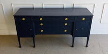 Load image into Gallery viewer, This vintage genuine mahogany sideboard combines generous storage with elegant Federal-inspired detailing. Professionally lacquered in Benjamin Moore In the Navy, its deep, classic navy finish highlights the fluted frieze, carved rosettes, decorative urn motifs, and slender tapered legs. New brass hardware. Good Bones Furniture
