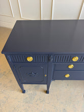 Load image into Gallery viewer, This vintage genuine mahogany sideboard combines generous storage with elegant Federal-inspired detailing. Professionally lacquered in Benjamin Moore In the Navy, its deep, classic navy finish highlights the fluted frieze, carved rosettes, decorative urn motifs, and slender tapered legs. New brass hardware. Good Bones Furniture

