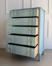 Load image into Gallery viewer, A classic French Provincial silhouette refreshed with a clean, modern lacquer finish. This vintage five-drawer chest features softly shaped drawer fronts, a gently serpentine apron, and cabriole-style feet that give it an elegant, airy profile. Finished in a custom Parma Gray mix, the color reads as a sophisticated blue-gray that shifts beautifully with natural light, and it’s completed with polished brass ginkgo leaf hardware for a warm, sculptural contrast. Good Bones Furniture
