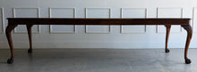 Load image into Gallery viewer, A timeless Henredon dining table crafted with exceptional attention to detail and beautiful figured mahogany veneers. The richly grained top showcases dramatic cathedral patterns framed by a contrasting mahogany border, while the carved cabriole legs with ball-and-claw feet reflect classic Chippendale-inspired design. Good Bones Furniture
