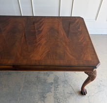 Load image into Gallery viewer, A timeless Henredon dining table crafted with exceptional attention to detail and beautiful figured mahogany veneers. The richly grained top showcases dramatic cathedral patterns framed by a contrasting mahogany border, while the carved cabriole legs with ball-and-claw feet reflect classic Chippendale-inspired design. Good Bones Furniture
