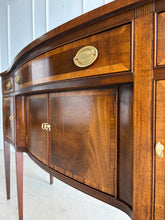 Load image into Gallery viewer, Vintage Hickory Chair sideboard showcasing classic Federal-inspired styling with beautifully banded mahogany veneers, graceful serpentine lines, and tapered legs. The thoughtfully designed layout includes three drawers above three cabinet compartments, offering versatile storage for dining essentials, serving pieces, or barware. Rich mahogany grain, satin brass hardware, and refined inlay details. Good Bones Furniture
