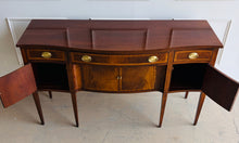 Load image into Gallery viewer, Vintage Hickory Chair sideboard showcasing classic Federal-inspired styling with beautifully banded mahogany veneers, graceful serpentine lines, and tapered legs. The thoughtfully designed layout includes three drawers above three cabinet compartments, offering versatile storage for dining essentials, serving pieces, or barware. Rich mahogany grain, satin brass hardware, and refined inlay details. Good Bones Furniture
