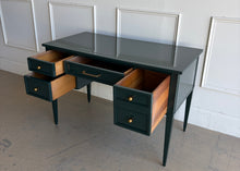 Load image into Gallery viewer, This beautifully refinished vintage desk offers timeless design with a fresh, designer-inspired finish. Professionally lacquered in Sherwin-Williams Rookwood Sash Green in a high-gloss sheen, it makes a bold yet sophisticated statement while preserving its classic mid-century silhouette. Five spacious drawers provide practical storage for office essentials, and the new antiqued brass hardware adds warmth and elegance against the rich green lacquer. Good Bones Furniture
