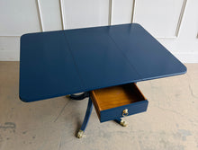 Load image into Gallery viewer, Classic Federal-inspired styling meets a fresh designer finish in this beautifully restored vintage drop leaf table. Professionally lacquered in Sherwin-Williams Naval, this versatile piece features two drop leaves that transform it from a slim console into a generous dining, game, or entry table in seconds. A single center drawer provides convenient storage, while the freshly painted lion head ring pull and polished brass claw feet add timeless elegance and character. Good Bones Furniture
