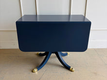 Load image into Gallery viewer, Classic Federal-inspired styling meets a fresh designer finish in this beautifully restored vintage drop leaf table. Professionally lacquered in Sherwin-Williams Naval, this versatile piece features two drop leaves that transform it from a slim console into a generous dining, game, or entry table in seconds. A single center drawer provides convenient storage, while the freshly painted lion head ring pull and polished brass claw feet add timeless elegance and character. Good Bones Furniture

