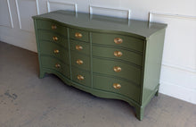 Load image into Gallery viewer, This vintage mahogany dresser makes a strong statement with its elegant serpentine front and generous twelve-drawer layout. The shaped case gives the piece movement and softness, while the symmetrical drawer configuration keeps the overall look balanced and refined. Professionally lacquered in Farrow &amp; Ball Bancha, the finish brings a rich olive green depth that feels classic, tailored, and quietly dramatic. Good Bones Furniture
