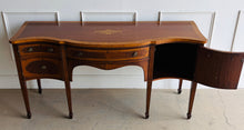 Load image into Gallery viewer, This vintage mahogany sideboard features graceful serpentine lines and exquisite satinwood inlay that highlight its timeless Federal-inspired design. The shaped top showcases a delicate inlaid urn motif, while bowed drawer fronts and paneled cabinet doors add depth and character throughout. A center drawer is flanked by two drawers above spacious side cabinets, providing generous storage for dining essentials or entertaining pieces. Good Bones Furniture

