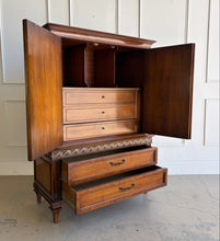 Load image into Gallery viewer, This vintage Mediterranean armoire has bold 1970s Spanish Revival styling with carved frieze detail, stepped door panels, burl veneer accents, and original brass ring hardware. The warm walnut-toned finish highlights the depth of the veneer, while the interior offers generous concealed storage with built-in drawers. Good Bones Furniture
